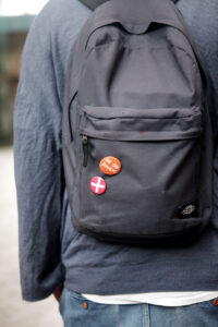 Back of person with backpack with two HIV awareness badges.